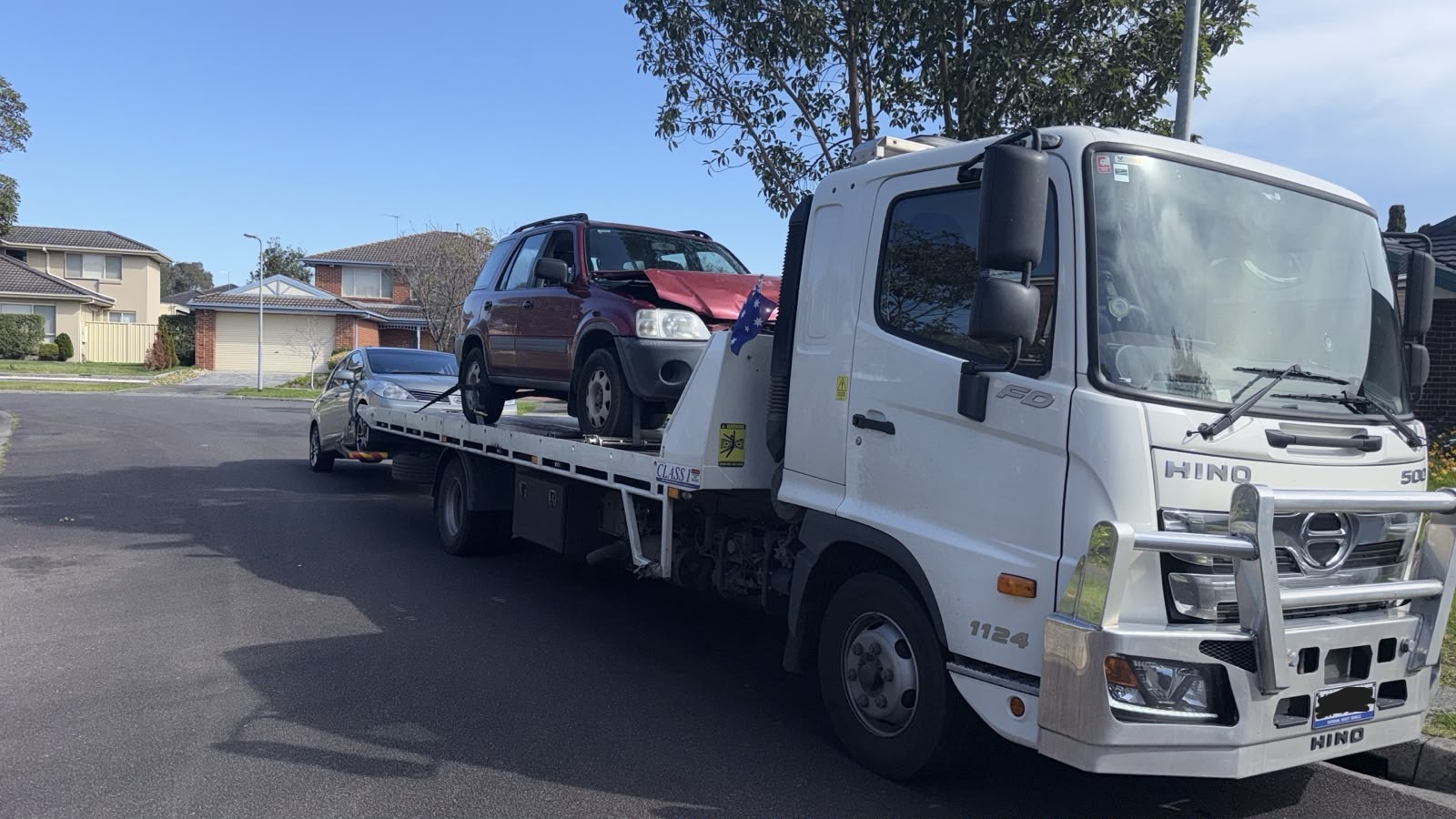 Red car loaded on a True Blue tilt tray truck on an Adelaide street